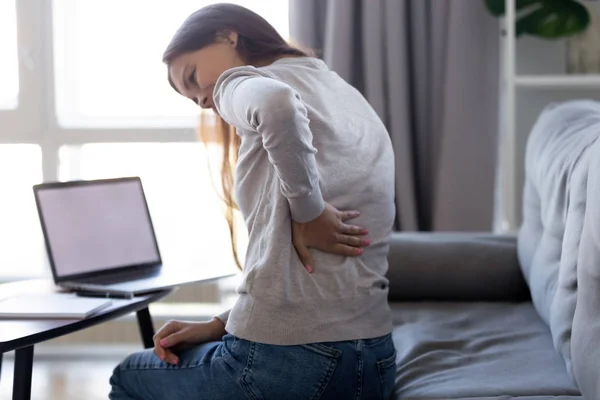 Jovem sentindo dor nas costas após o trabalho sedentário do computador em casa — Fotografia de Stock