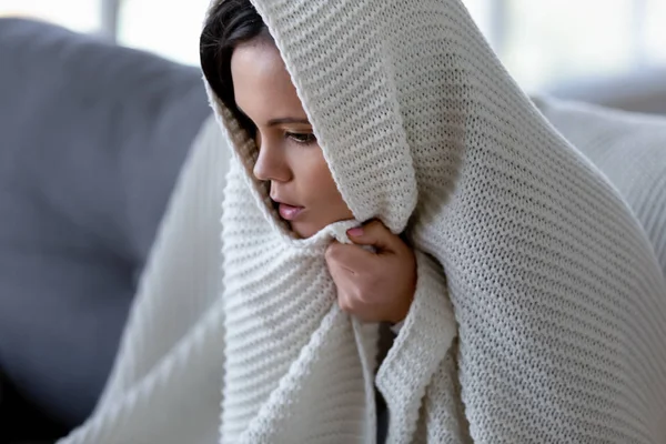 Ill woman feeling cold having flu symptoms covered with blanket