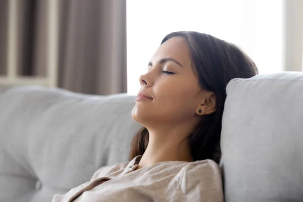 Ruhige Frau entspannt auf bequemer Couch beim Mittagsschlaf angelehnt — Stockfoto