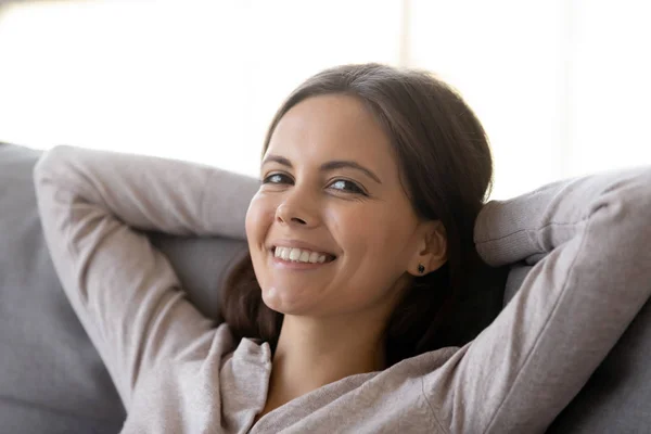 Relaxed young woman resting leaning on couch looking at camera — Stock Photo, Image