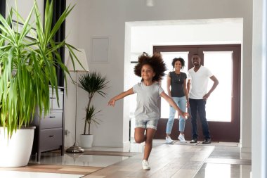 Biraz komik Afrikalı kız keşfetmek büyük modern ev içinde mutlu siyah ebeveyn ve çocuk kızı koridorda, Aile ipotek eğleniyor şirin karışık yarış çocuk yeni evine gelen hareket çalıştıran heyecanlı