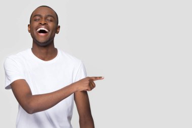 Happy african man laughing pointing finger aside at copy space clipart