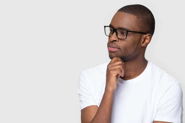 Thoughtful african man holding hand on chin looking at copyspace — Stock Photo, Image