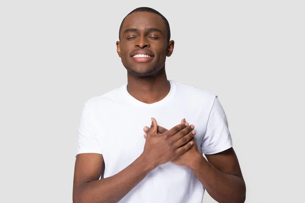Grateful happy african man holding hands on chest feeling appreciation — Stock Photo, Image