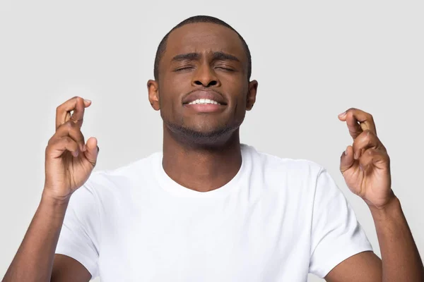 Hoopvol jonge Afrikaanse man kruising vingers wensen voor goed geluk — Stockfoto