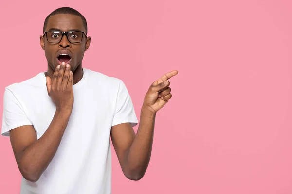 Shocked black man with open mouth pointing at copyspace aside — Stock Photo, Image