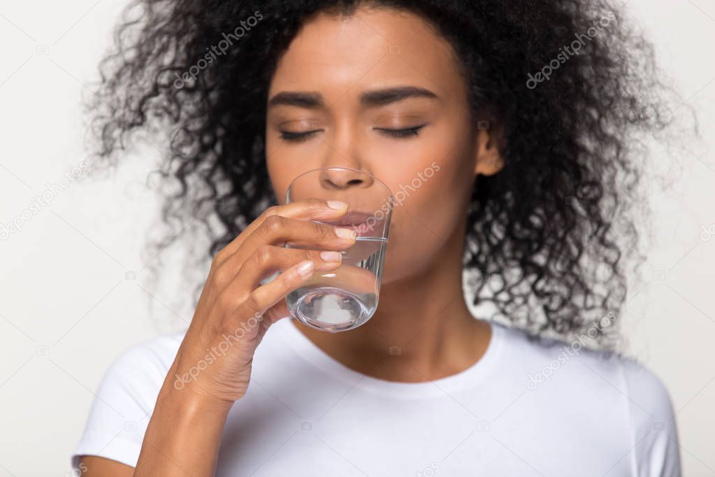 Healthy thirsty african woman drinking water isolated on white background