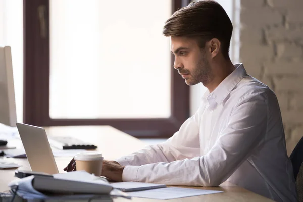 Koncentruje się mężczyzna pracownik zajęty pracą na laptopie w biurze — Zdjęcie stockowe