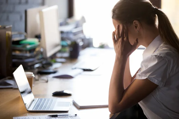強い頭痛に苦しむ寺院 マッサージのオフィスの机で疲れ果てた女性従業員座る 疲れている女性労働者の感じ悪い偏頭痛や高血圧を有する作業がリラックスできるから休憩を取る — ストック写真