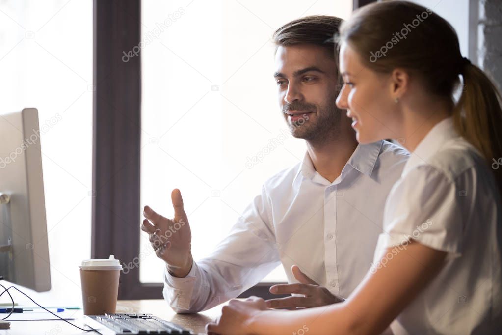 Colleagues negotiate looking at computer in office
