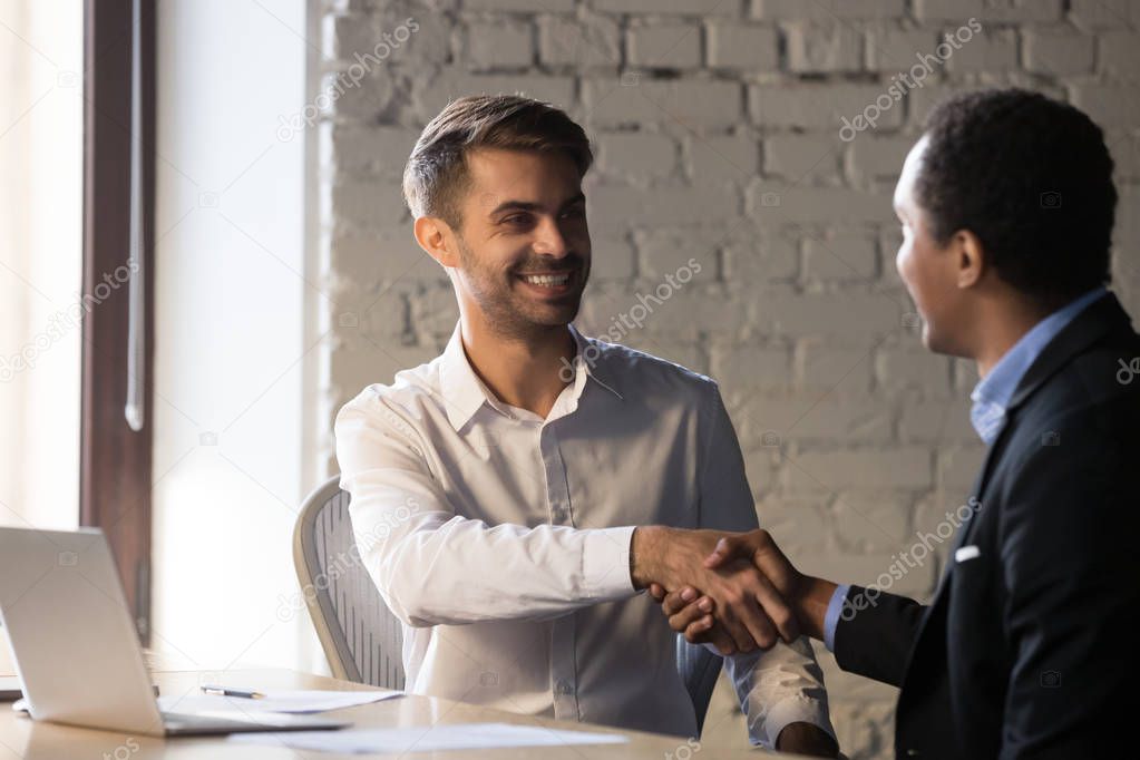 Excited businessman handshake male applicant at job interview