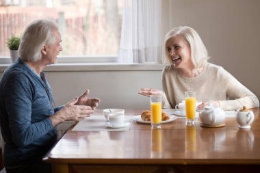 Yaşlı çift eğleniyor mutfakta yemek kahvaltı oturan gülüyor