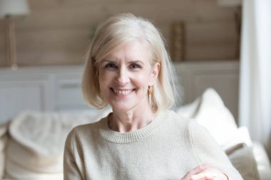 Gülümseyen kadın kameraya bakarak oturma odasında oturan yaşlı