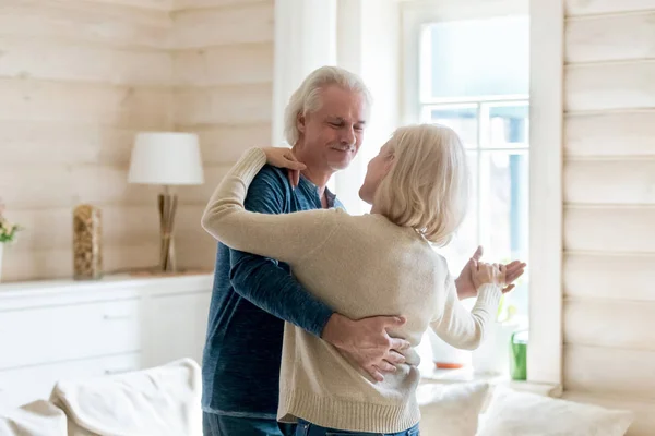Happy aged spouses standing in living room and dancing tango — Stock Photo, Image