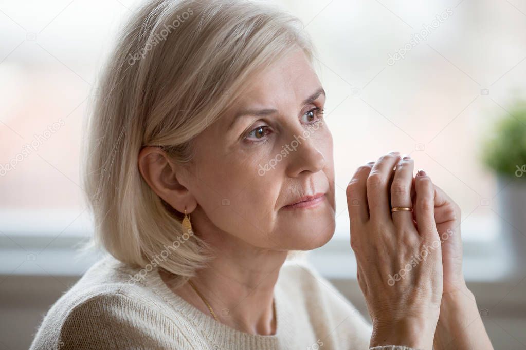 Close up portrait of beautiful sad woman folding hands together near her face, thinking about life. Aging is period of physical decline and senile dementia, mental disorders emotional problems concept