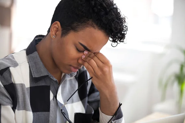 Mujer africana cansada quitándose las gafas siente tensión en los ojos — Foto de Stock