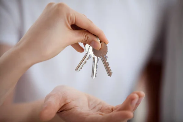 Broker hand holding keys giving to new home owner, closeup