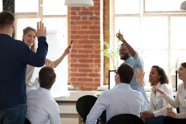 Business people raising hands voting asking questions at corporate training