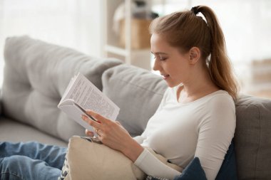 Gülümseyen genç hippi kız kitap roman kanepede oturan okuma