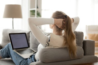 Rahat kadın kanepede dizüstü bilgisayar ile dinlenme, arka görüş