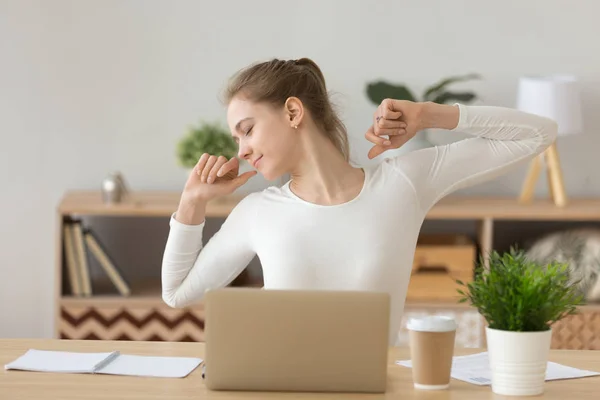 Relaxed woman stretching at desk satisfied with job well done