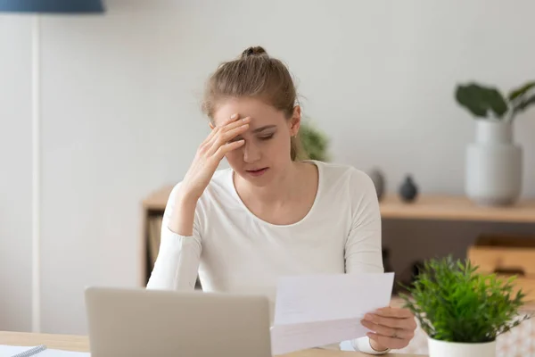 Traurige junge Frau liest schlechte Nachrichten in Papierbrief — Stockfoto