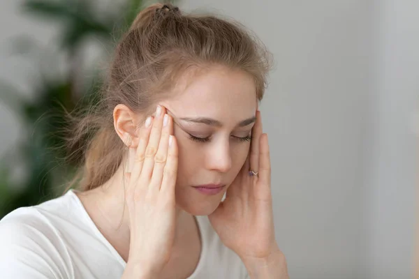 Young fatigued woman having strong headache suffering from chronic migraine