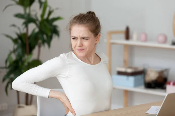 Menina cansada sentindo dor nas costas esfregando músculos após o trabalho sedentário — Fotografia de Stock