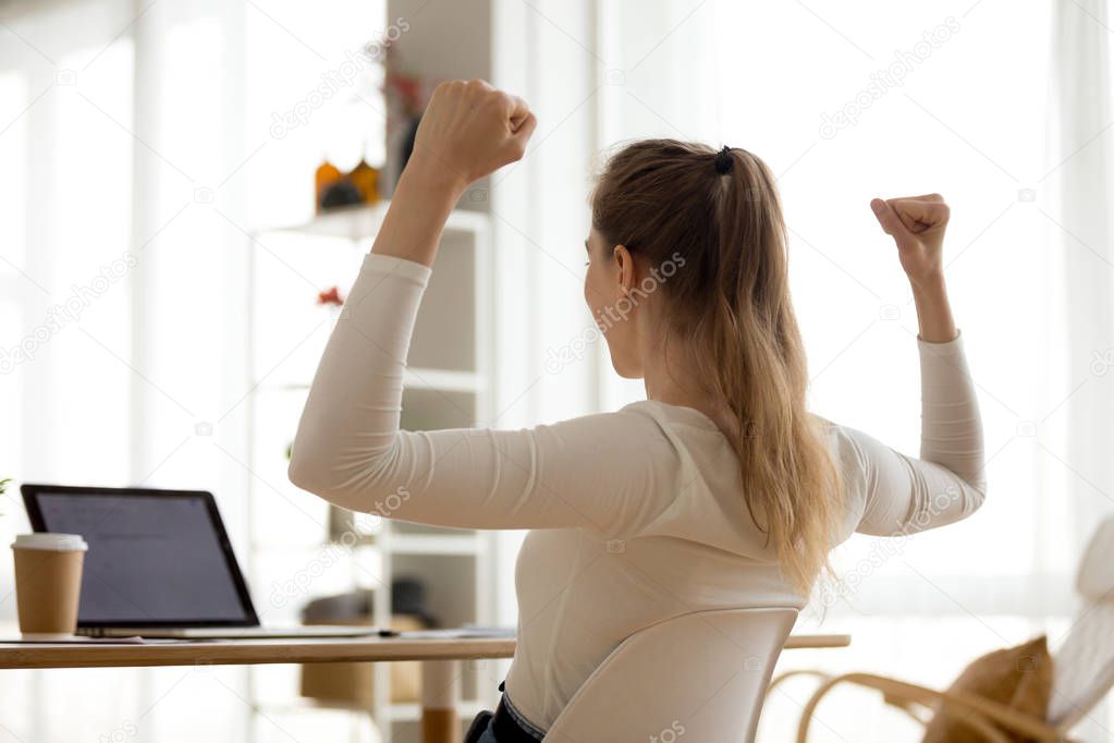 Rear view at excited woman reading good news in email