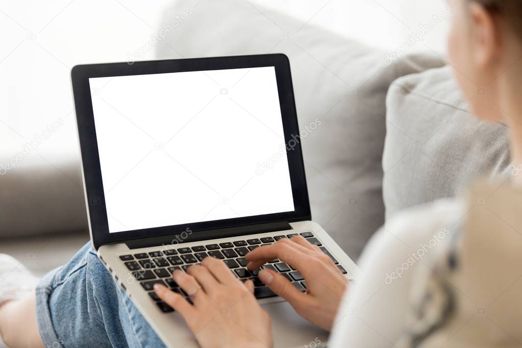 Woman using laptop with blank mockup screen at home
