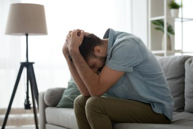 Depresif üzgün adam kafa elinde tutan kanepede oturan
