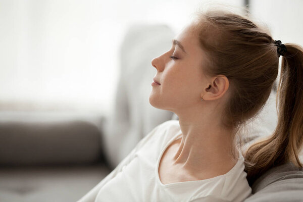 Happy calm woman relaxing breathing fresh air dreaming on couch