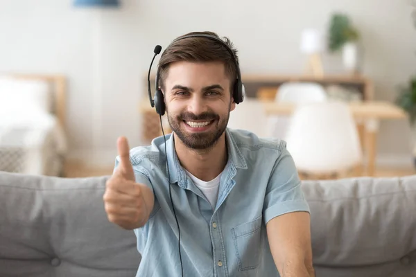 Happy young man wearing headset showing thumbs up giving recommendation — Stock Photo, Image
