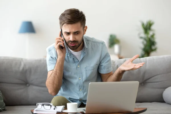 Arg man pratar på telefon tvista om dator laptop problem — Stockfoto