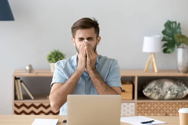 Ill at work young man got flu sneezing blowing nose — Stock Photo, Image