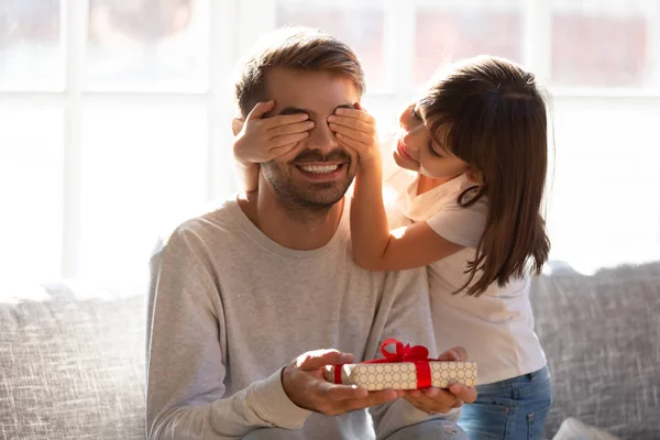 Niño hija cubriendo los ojos de feliz papá sosteniendo caja de regalo — Foto de Stock