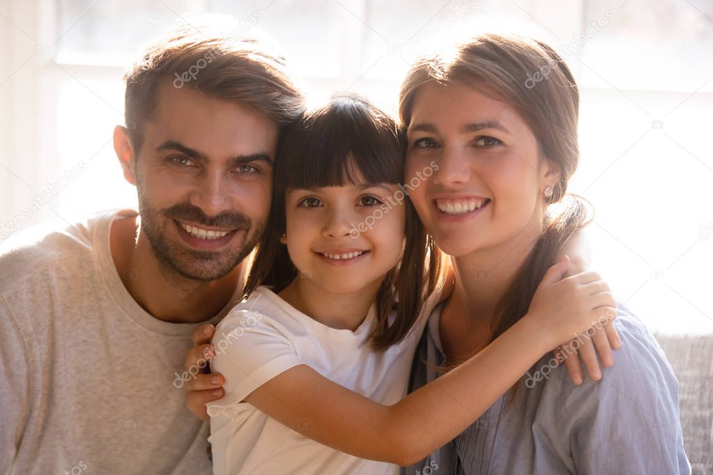 Happy mom dad and little daughter with smiling faces portrait