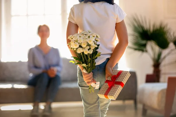 抱着鲜花和礼品盒的孩子女儿的后视镜 — 图库照片