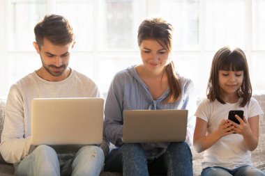 Anne ve çocuk kızı evde dizüstü bilgisayarlar ve akıllı telefon kullanma