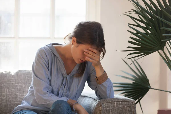 Upset depressed woman feeling tired having headache sitting on couch — Stock Photo, Image