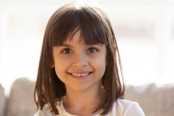 Aranyos kis lány mosolyogva nézett kamera beltéri, portré fejlövés — Stock Fotó