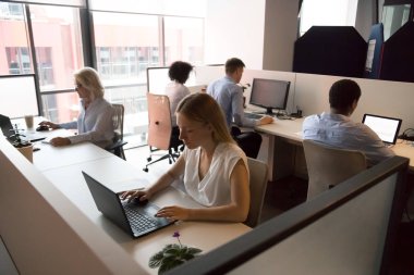 Employees working in coworking office sitting at desk using computers clipart