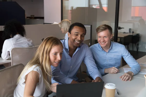 Trois employés joyeux travaillant dans une salle de coworking à l'aide d'un ordinateur — Photo