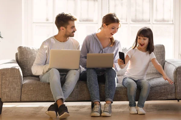 Excited child girl holding smartphone showing amazed parents surprising app — Stock Photo, Image