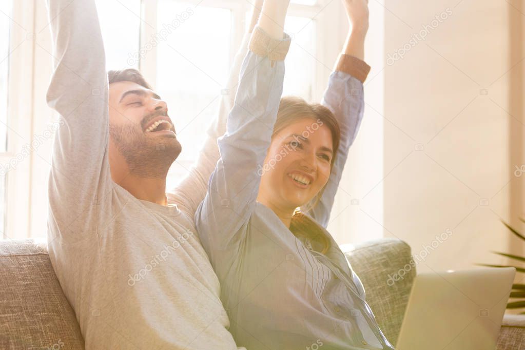 Overjoyed couple celebrating  online betting bid win sitting on couch