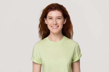 Kameraya bakarak t-shirt giyen gülümseyen Kızıl saçlı genç kız öğrenci