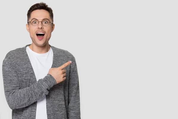 Hombre sorprendido en gafas señalando con el dedo a un lado mirando a la cámara — Foto de Stock