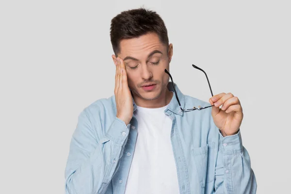 Jeune homme bouleversé sentant fatigue oculaire ou mal de tête enlever des lunettes — Photo