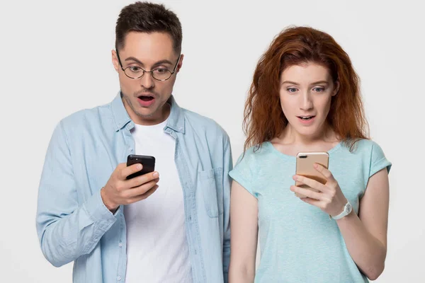 モバイル アプリケーション sms の申し出に驚いて電話を保持している驚きのカップル — ストック写真
