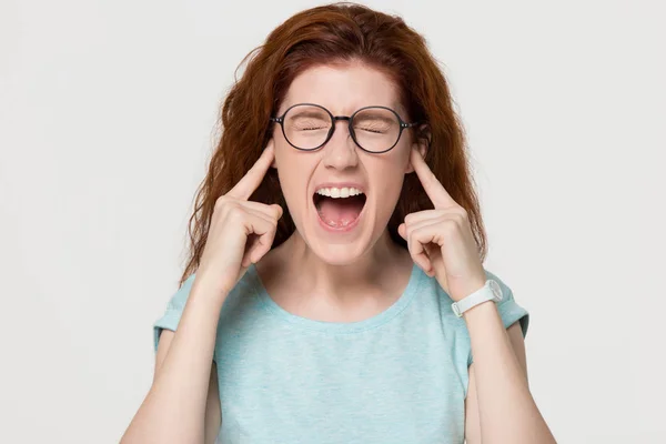 Uparta zły redhead dziewczyna trzymać palce plug w uszy krzyk — Zdjęcie stockowe